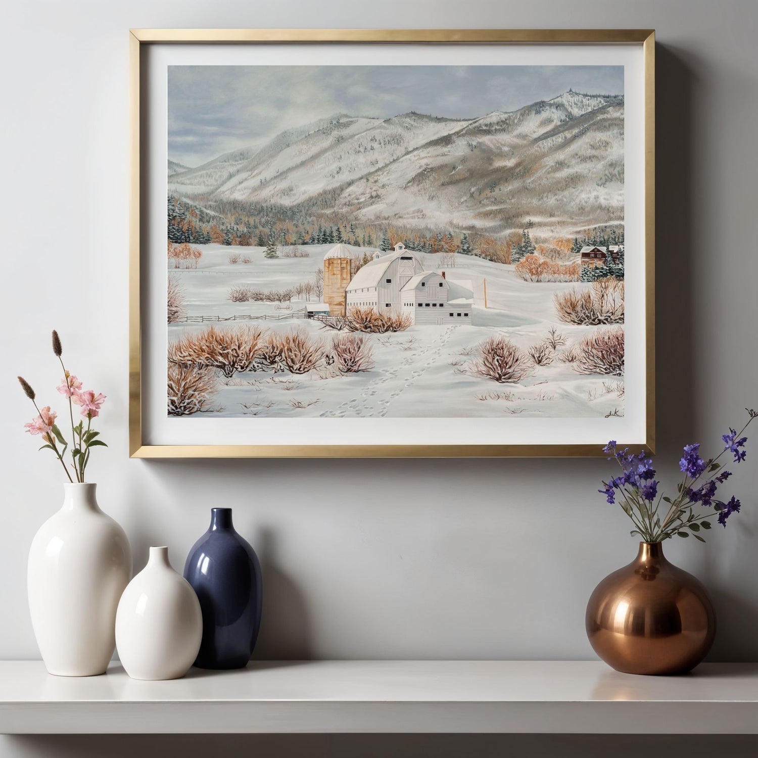Framed winter landscape painting on a wall with decorative vases below.